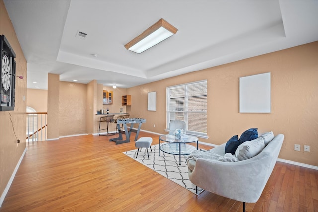 living room featuring a raised ceiling and light hardwood / wood-style flooring