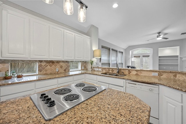 kitchen featuring white dishwasher, white cabinets, stainless steel cooktop, sink, and hanging light fixtures