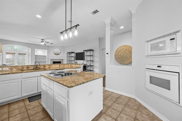 kitchen with white cabinetry, sink, a center island, decorative light fixtures, and white appliances