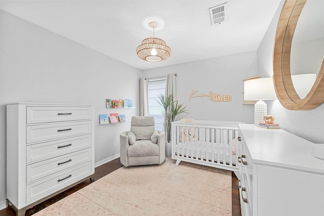 bedroom with a nursery area and dark hardwood / wood-style floors