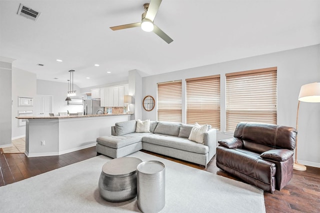 living room featuring ceiling fan and dark wood-type flooring