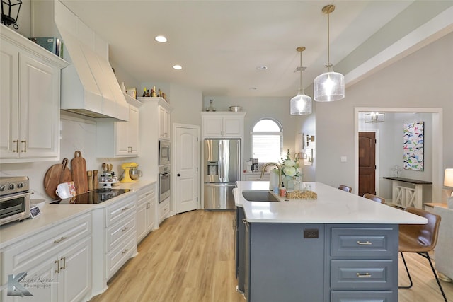 kitchen featuring pendant lighting, a kitchen bar, stainless steel appliances, white cabinets, and a center island with sink