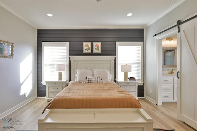 bedroom featuring crown molding, a barn door, and light hardwood / wood-style floors