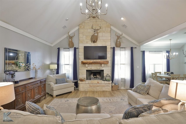 living room featuring light hardwood / wood-style flooring, high vaulted ceiling, ornamental molding, a stone fireplace, and a chandelier