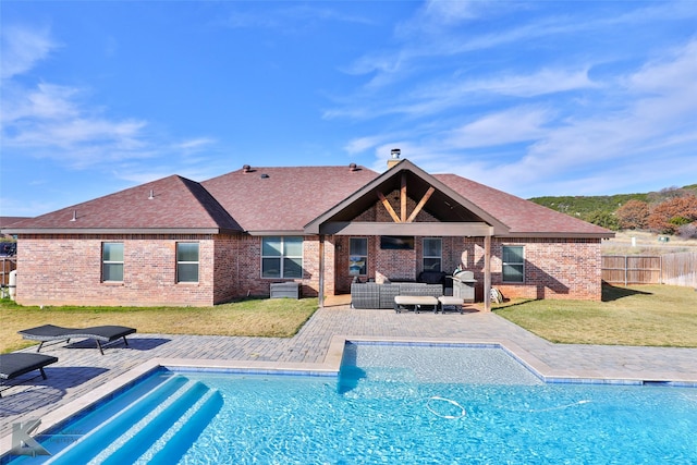 rear view of property featuring a fenced in pool, a patio, an outdoor hangout area, and a lawn