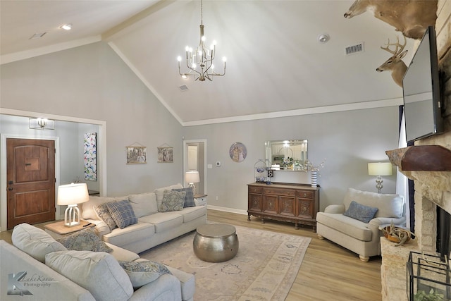 living room featuring a stone fireplace, high vaulted ceiling, a notable chandelier, and light wood-type flooring