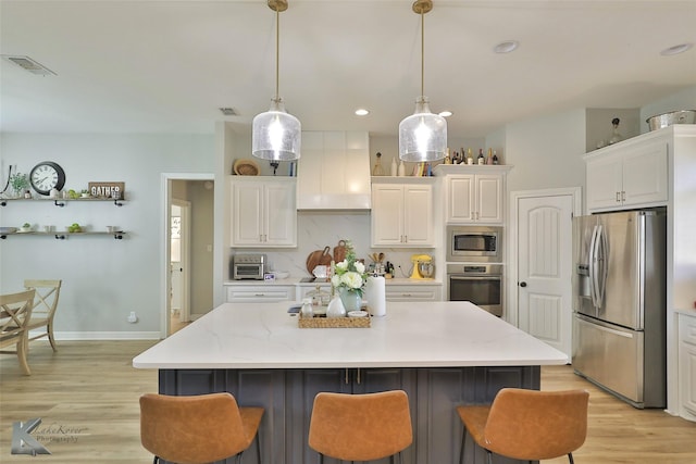 kitchen with a kitchen island, pendant lighting, white cabinets, backsplash, and stainless steel appliances