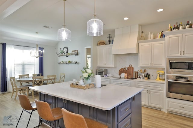 kitchen with stainless steel appliances, premium range hood, and white cabinets