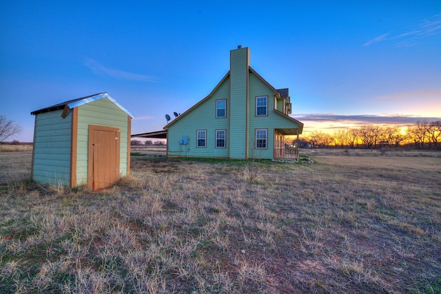 back house at dusk with a storage shed