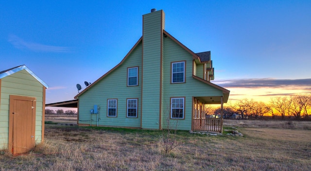 back house at dusk featuring a lawn