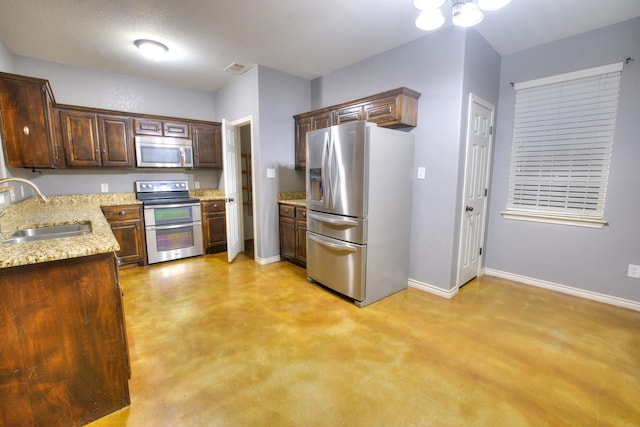 kitchen featuring light stone countertops, appliances with stainless steel finishes, dark brown cabinets, sink, and a notable chandelier