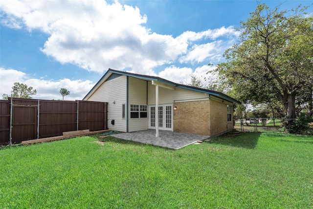 back of house featuring a lawn, a patio, and french doors