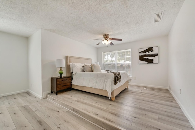 bedroom featuring a textured ceiling, light wood-type flooring, and ceiling fan