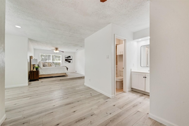 hallway with a textured ceiling and light hardwood / wood-style flooring