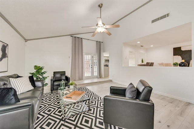 living room featuring ceiling fan, light hardwood / wood-style floors, ornamental molding, and vaulted ceiling