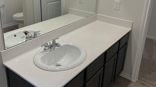 bathroom featuring hardwood / wood-style flooring, toilet, and vanity