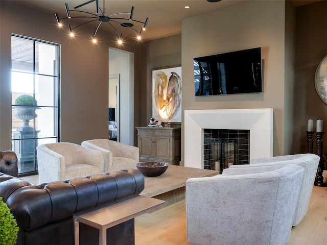 living room featuring a fireplace, light hardwood / wood-style flooring, and a chandelier