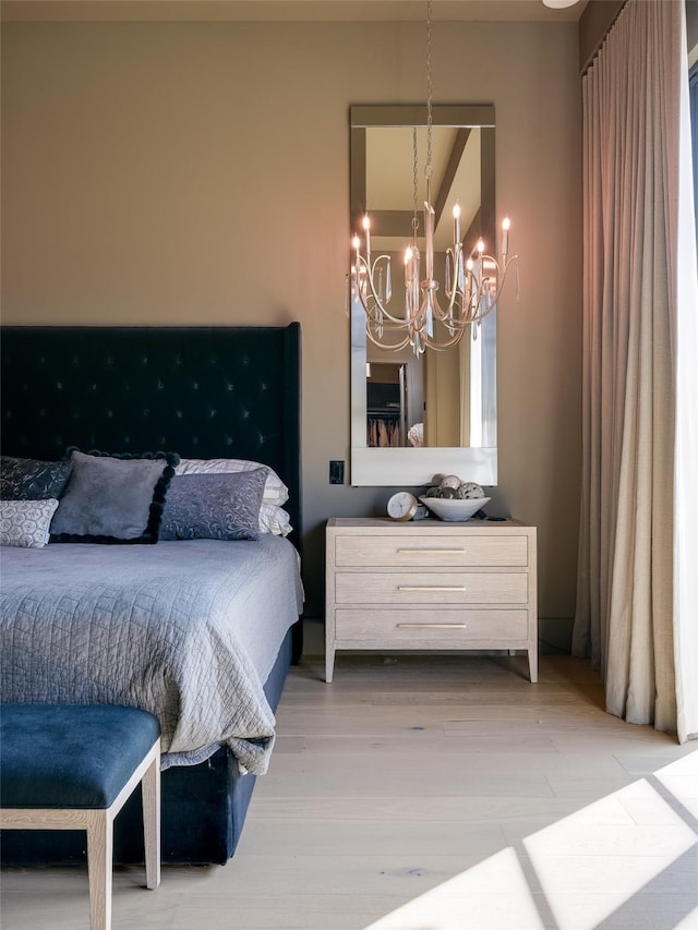 bedroom with light wood-type flooring and a notable chandelier