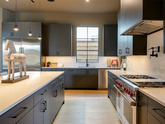 kitchen featuring pendant lighting, double oven range, sink, light hardwood / wood-style floors, and custom range hood