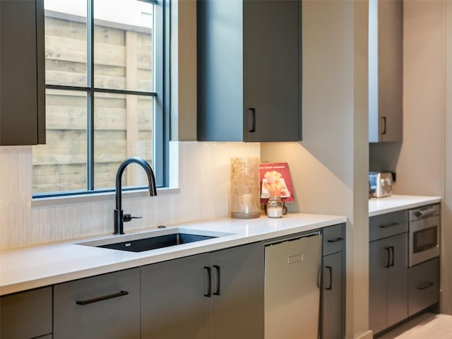 kitchen featuring backsplash, gray cabinetry, dishwasher, and sink