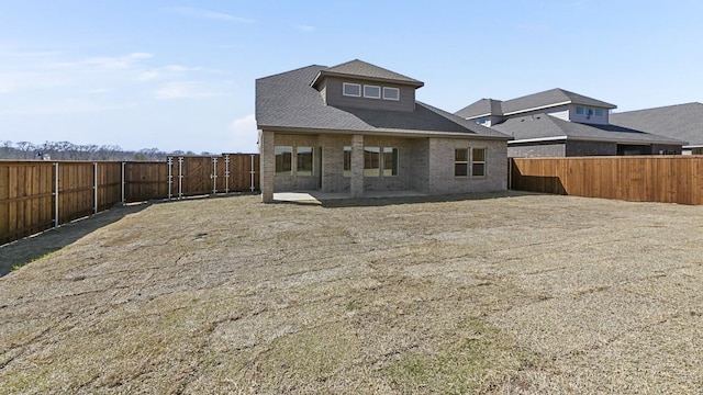 back of property with a patio, brick siding, roof with shingles, and a fenced backyard
