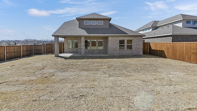 back of property with a patio, brick siding, a fenced backyard, and a shingled roof