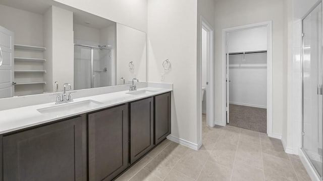 bathroom with a sink, a spacious closet, and a shower stall