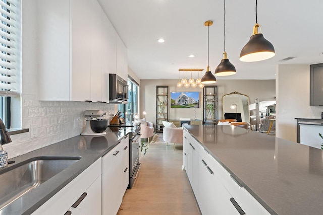 kitchen with white cabinetry, sink, stainless steel electric range oven, decorative light fixtures, and decorative backsplash