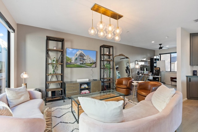 living room with ceiling fan, a wealth of natural light, and light hardwood / wood-style flooring