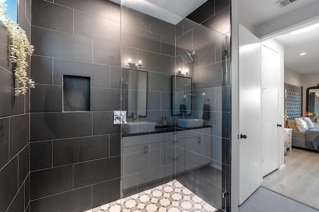 bathroom with tiled shower, wood-type flooring, and vanity