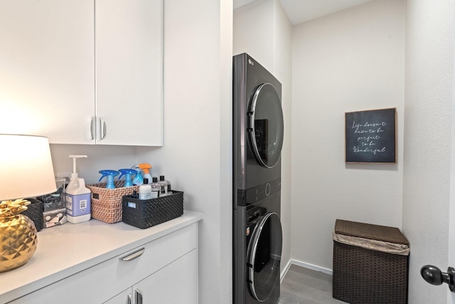 laundry room featuring cabinets, wood-type flooring, and stacked washer / dryer