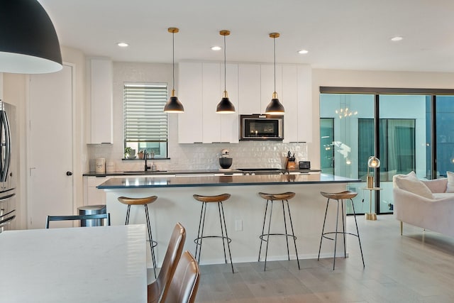 kitchen with white cabinets, sink, hanging light fixtures, and a breakfast bar area