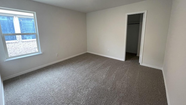 4237 Zayan Dr, Sherman, TX 75090 - unfurnished bedroom featuring multiple windows, dark colored carpet, a walk in closet, and baseboards