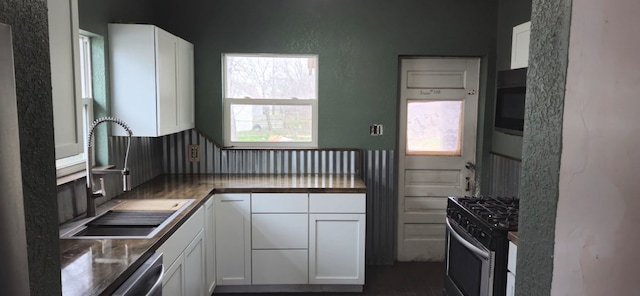 kitchen with appliances with stainless steel finishes, white cabinetry, and sink