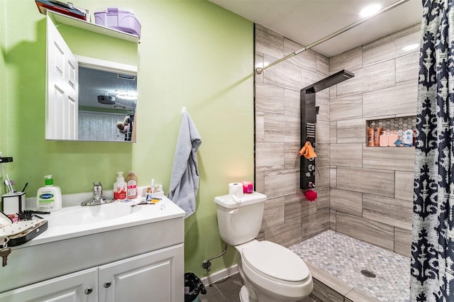 bathroom featuring vanity, toilet, and a tile shower