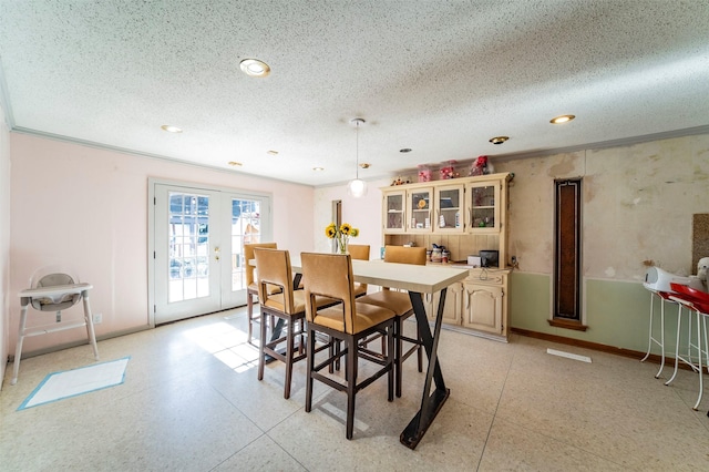 dining space with french doors, a textured ceiling, and crown molding