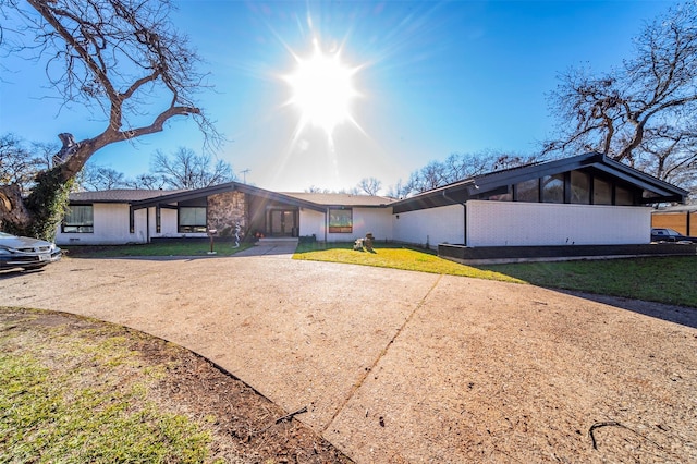 ranch-style home featuring a sunroom and a front lawn