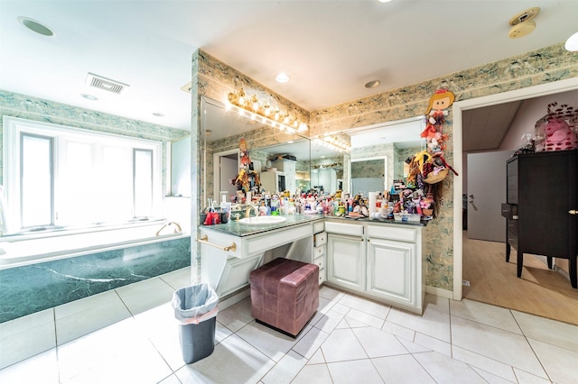 bathroom with tile patterned floors, a tub to relax in, and vanity