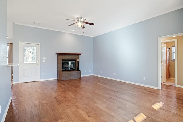 unfurnished living room featuring ceiling fan, light wood-type flooring, ornamental molding, and a brick fireplace