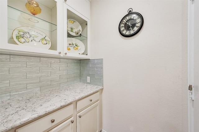 interior space with light stone counters, backsplash, and white cabinets