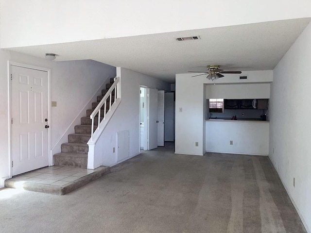 unfurnished living room featuring a textured ceiling, ceiling fan, and carpet flooring