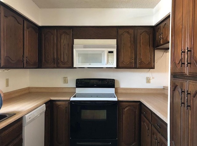 kitchen with dark brown cabinets, white appliances, and a textured ceiling