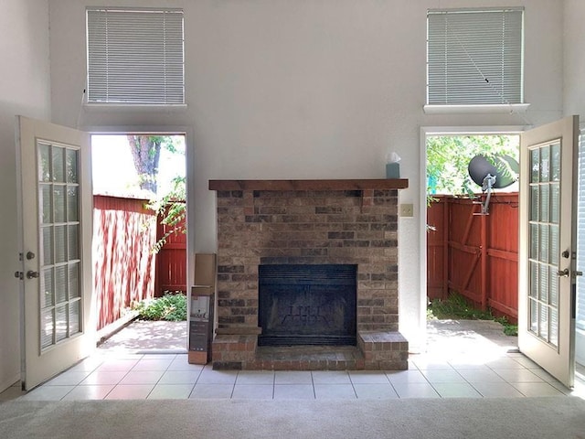 interior space featuring french doors, a fireplace, light tile patterned floors, and a high ceiling