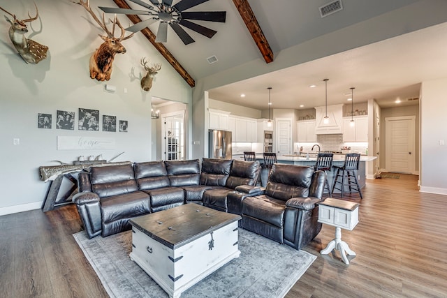 living room with ceiling fan, sink, beamed ceiling, high vaulted ceiling, and hardwood / wood-style flooring