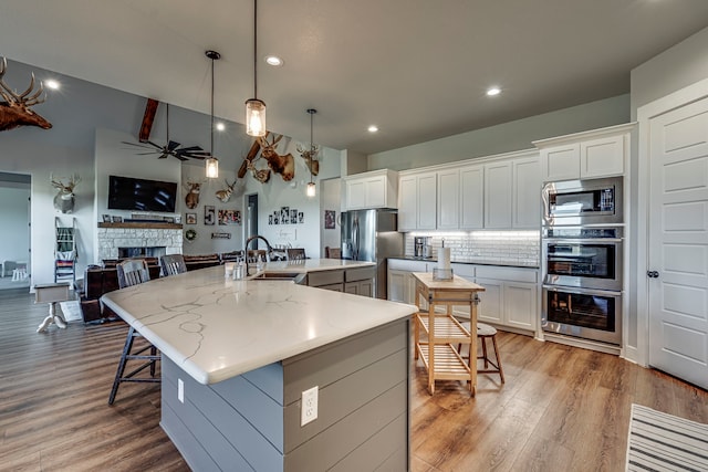 kitchen featuring decorative light fixtures, sink, white cabinetry, and an island with sink