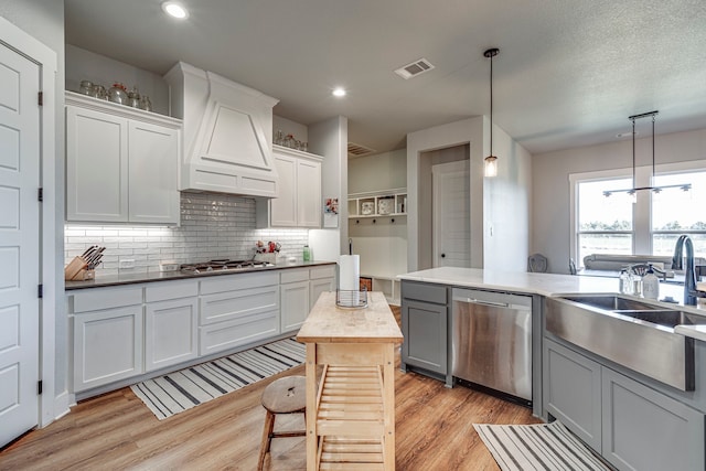 kitchen with a center island, stainless steel appliances, pendant lighting, white cabinets, and custom exhaust hood