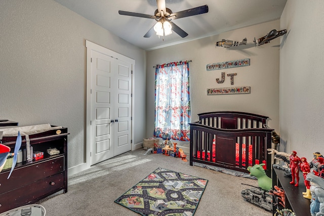 carpeted bedroom featuring ceiling fan and a crib