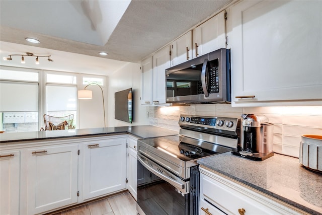 kitchen featuring white cabinetry, backsplash, stainless steel appliances, a textured ceiling, and light wood-type flooring