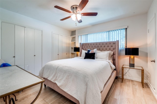 bedroom featuring two closets, ceiling fan, and light hardwood / wood-style flooring