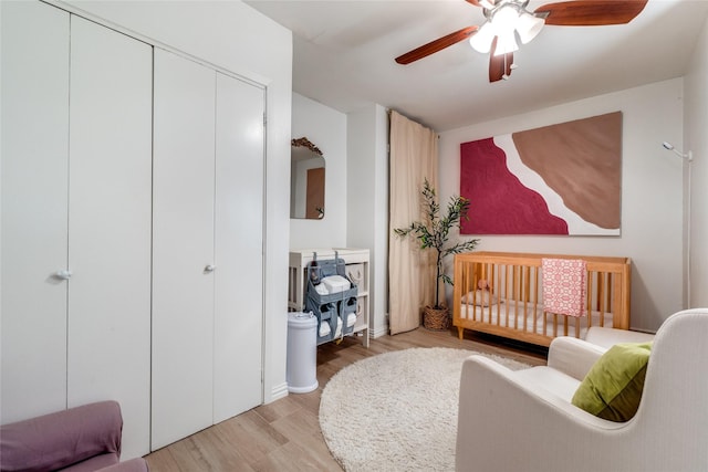 bedroom featuring ceiling fan, light hardwood / wood-style flooring, and a crib